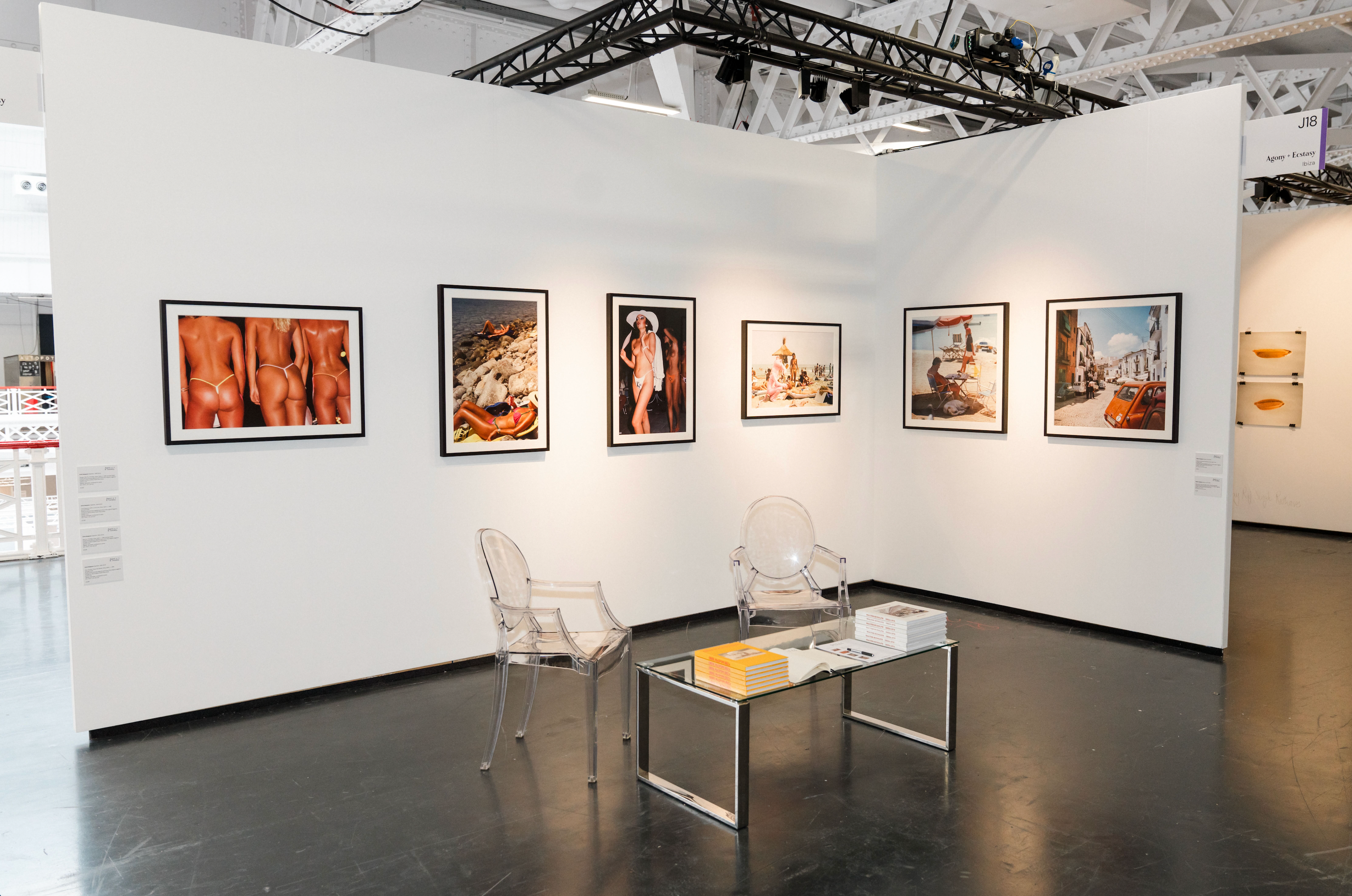 Art gallery with framed photographs on the walls and a clear chair in the center.